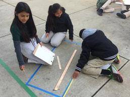 Students measuring and collaborating outdoors during a math and literacy activity