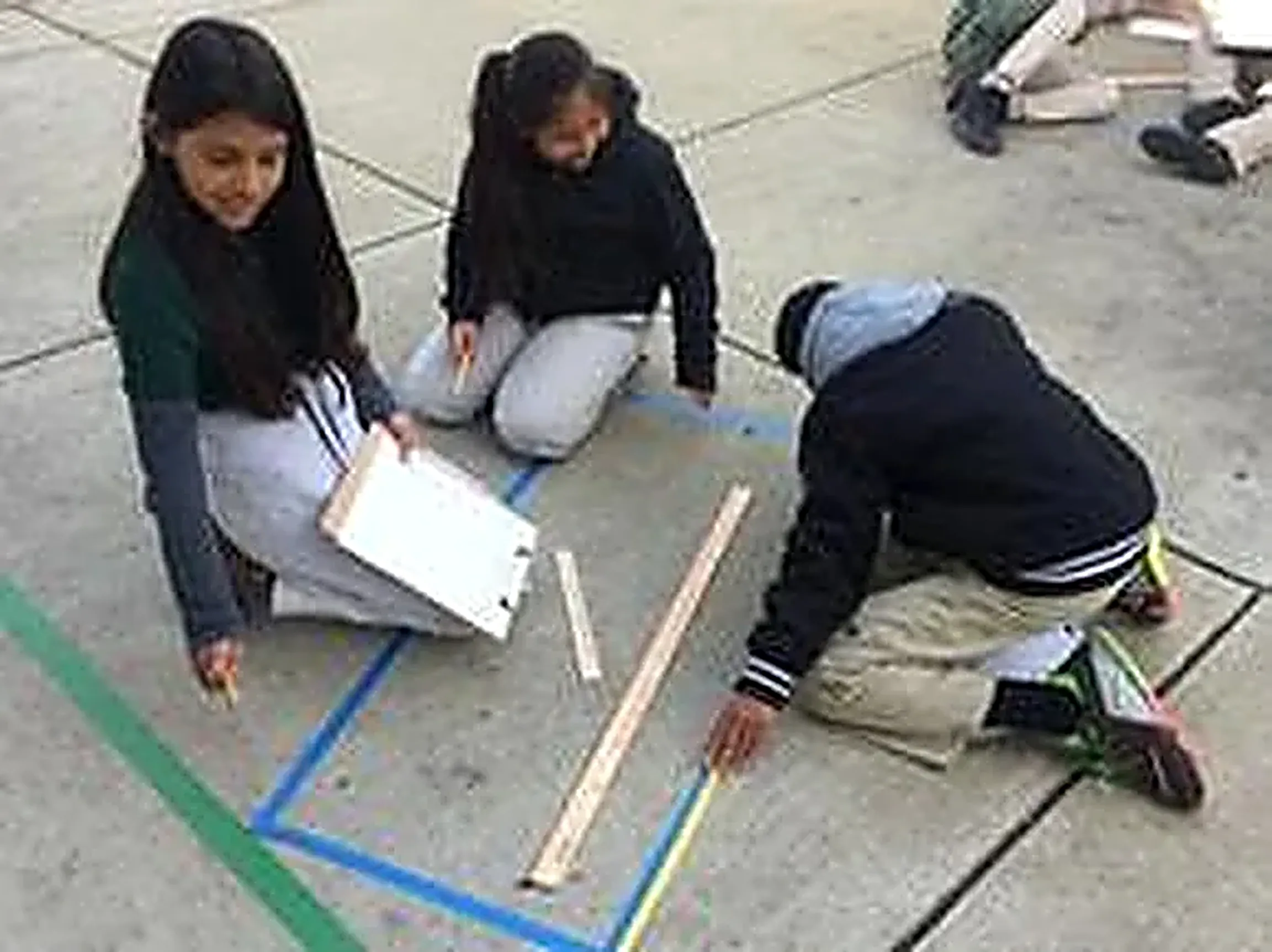 Students measuring and collaborating outdoors during a math and literacy activity