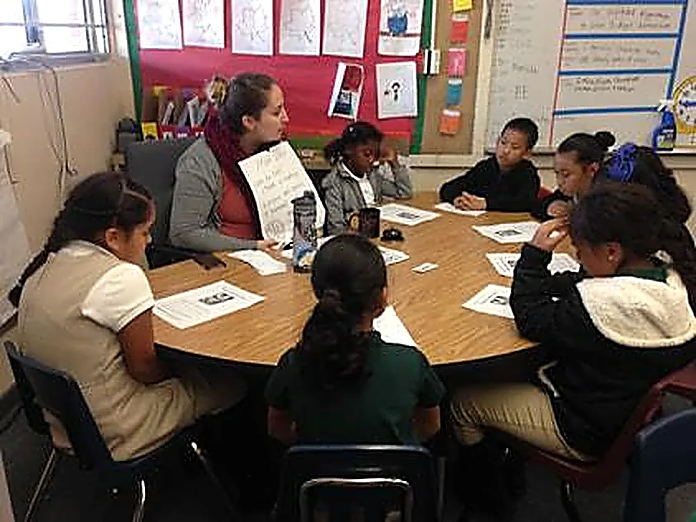 A teacher leading a small-group literacy discussion at a round table