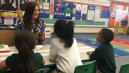 A teacher leading a small-group literacy lesson with students at a table