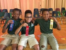 Students holding award ribbons together on stage