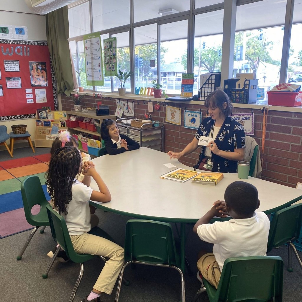 A teacher reading with elementary students at a classroom table