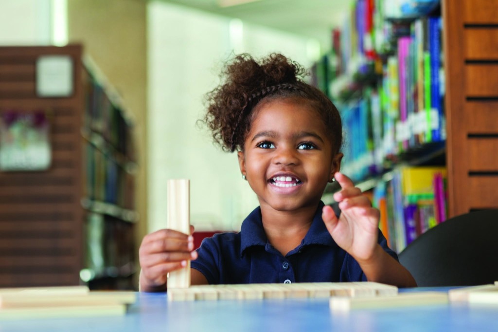 A student playing with wooden blocks in the school library